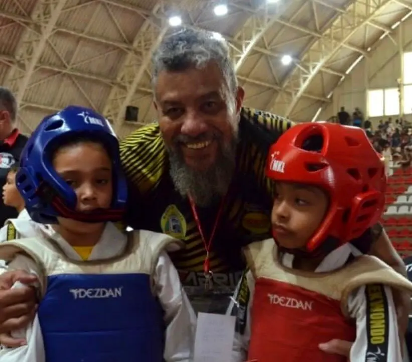 Professor com dois jovens atletas usando equipamentos de proteção